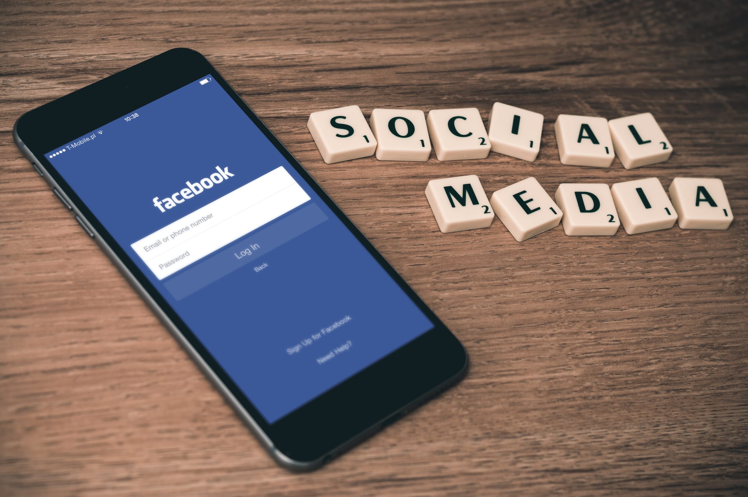 smartphone with Facebook app opened and social media spelled out of scrabble words